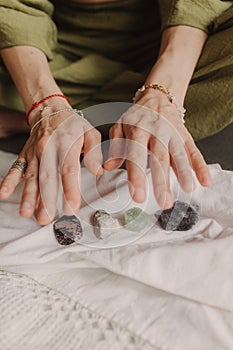 Woman holds jewelry made of natural stones in her hand, her hands are decorated with rings and bracelets. Handicrafts and