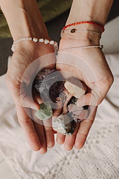 Woman holds jewelry made of natural stones in her hand, her hands are decorated with rings and bracelets. Handicrafts and