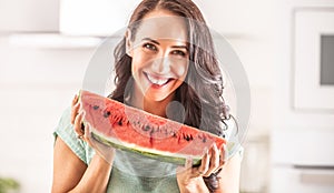 Woman holds a large piece of watermelon, smiling