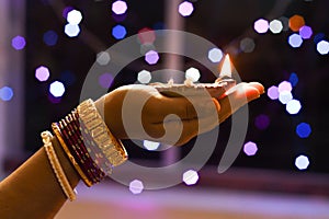 Woman holds lit earthen diwali lamp in one hand