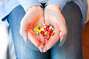Woman holds many multicolored pills in hands. Taking vitamins, supplements, antibiotic, antidepressant and painkiller medication.