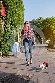 Fashionably dressed girl at the window of a boutique selling clothes. A woman holds a mini chihuahua in her arms. The pet is