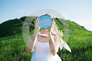 Woman holds mirror with sky reflection instead of head. Concept unity with nature, despair, loneliness, nostalgia, memories