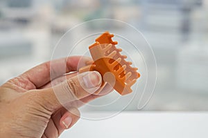 Woman holds orange hair clip for beauty with left hand