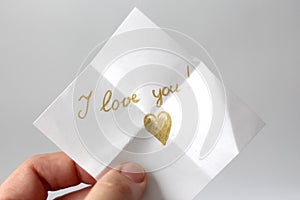 A woman holds a paper message with the text I love you