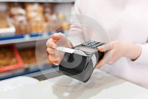 A woman holds a payment terminal while holding a receipt for completing a purchase. Hands close up. The concept of NFC, business