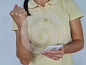 Woman holds phone, looks at screen shows a yes gesture closeup