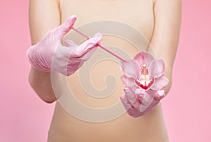A woman holds a pink orchid in her hands and makes injections for rejuvenation. The concept of plastic surgery