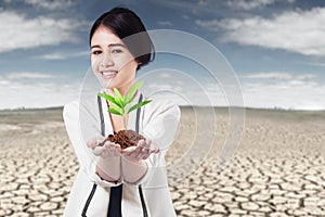 Woman holds plant at drought land