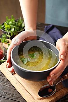 Woman holds plate of chicken soup, close up