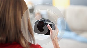 Woman holds professional black camera in hands and photographs model at home photo