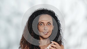 Woman holds a roller lifting gel. Longhaired curly woman in the studio on a gray background with highlights close up