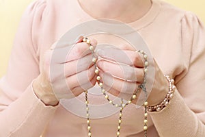 Woman holds a rosary in her hands