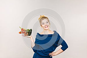 Woman holds shopping basket with vegetables