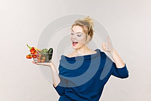 Woman holds shopping basket with vegetables