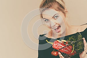 Woman holds shopping basket with vegetables