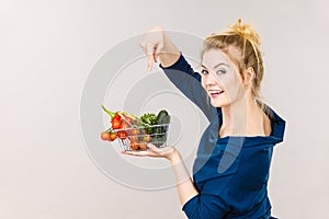 Woman holds shopping basket with vegetables