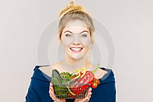 Woman holds shopping basket with vegetables