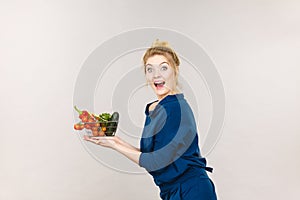 Woman holds shopping basket with vegetables