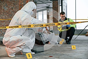 Woman holds the sleeve from the cartridge and puts it in the bag. Detectives are collecting evidence in a crime scene near dead