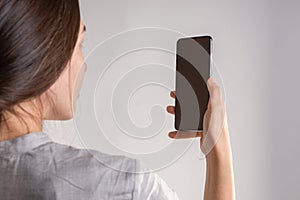 woman holds a smartphone in front of her eyes, use the app or take a photo.