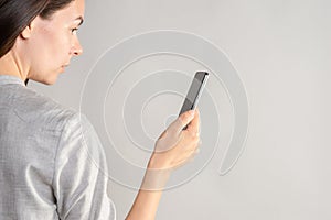 woman holds a smartphone in front of her eyes, use the app or take a photo.