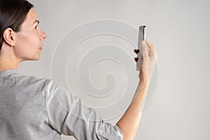 woman holds a smartphone in front of her eyes, use the app or take a photo.
