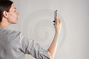 woman holds a smartphone in front of her eyes, use the app or take a photo.