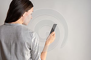 woman holds a smartphone in front of her eyes, use the app or take a photo.