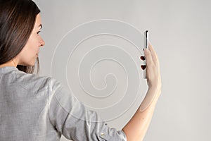 woman holds a smartphone in front of her eyes, use the app or take a photo.