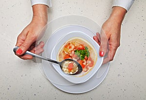 Woman holds spoon with soup