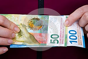 The woman holds Swiss money, 100 and 50 franc banknotes