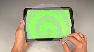 A woman holds a tablet PC with a green screen for your own custom content.