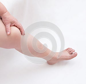 Woman holds on to a sore leg on a white background. The concept of diseases of blood vessels and arteries of the lower