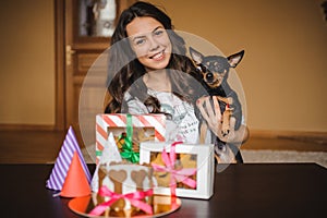 Woman holds toy terrier with dog cake and cookies on birthday party