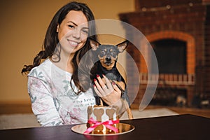 Woman holds toy terrier with dog cake infront on birthday party