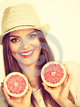 Woman holds two halfs of grapefruit citrus fruit in hands