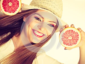 Woman holds two halfs of grapefruit citrus fruit in hands