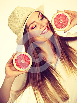 Woman holds two halfs of grapefruit citrus fruit in hands