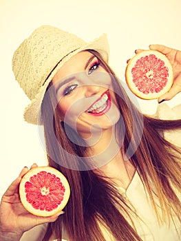 Woman holds two halfs of grapefruit citrus fruit in hands