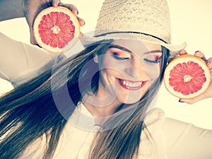 Woman holds two halfs of grapefruit citrus fruit in hands