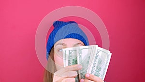 Woman holds US Dollars money bills pink background. Girl counting cash american 100 USD banknotes. Earning saving USA currency