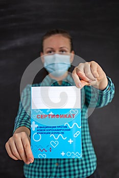 A woman holds a vaccination certificate in her hands. Russia, Russian text