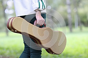 Woman holds violin and guitar case and walks through park