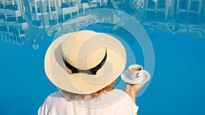 woman holds a white cup of coffee in her hands on the background of a blue swimming pool. Good morning enjoyment concept