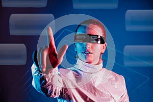 Woman in holographic clothes and futuristic eyeglasses with reflection touching or pressing by finger button with empty