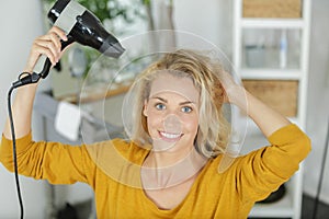 Woman at home blow drying hair