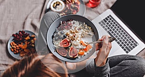 Woman in home clothes eating vegan Rice coconut porridge with figs, berries, nuts. Healthy breakfast ingredients