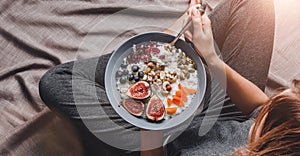 Woman in home clothes eating vegan Rice coconut porridge with figs, berries, nuts. Healthy breakfast ingredients. Clean eating