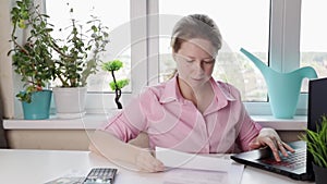 woman at home counting utility bills on a calculator, employee typing on her computer at her designated workstation, professional